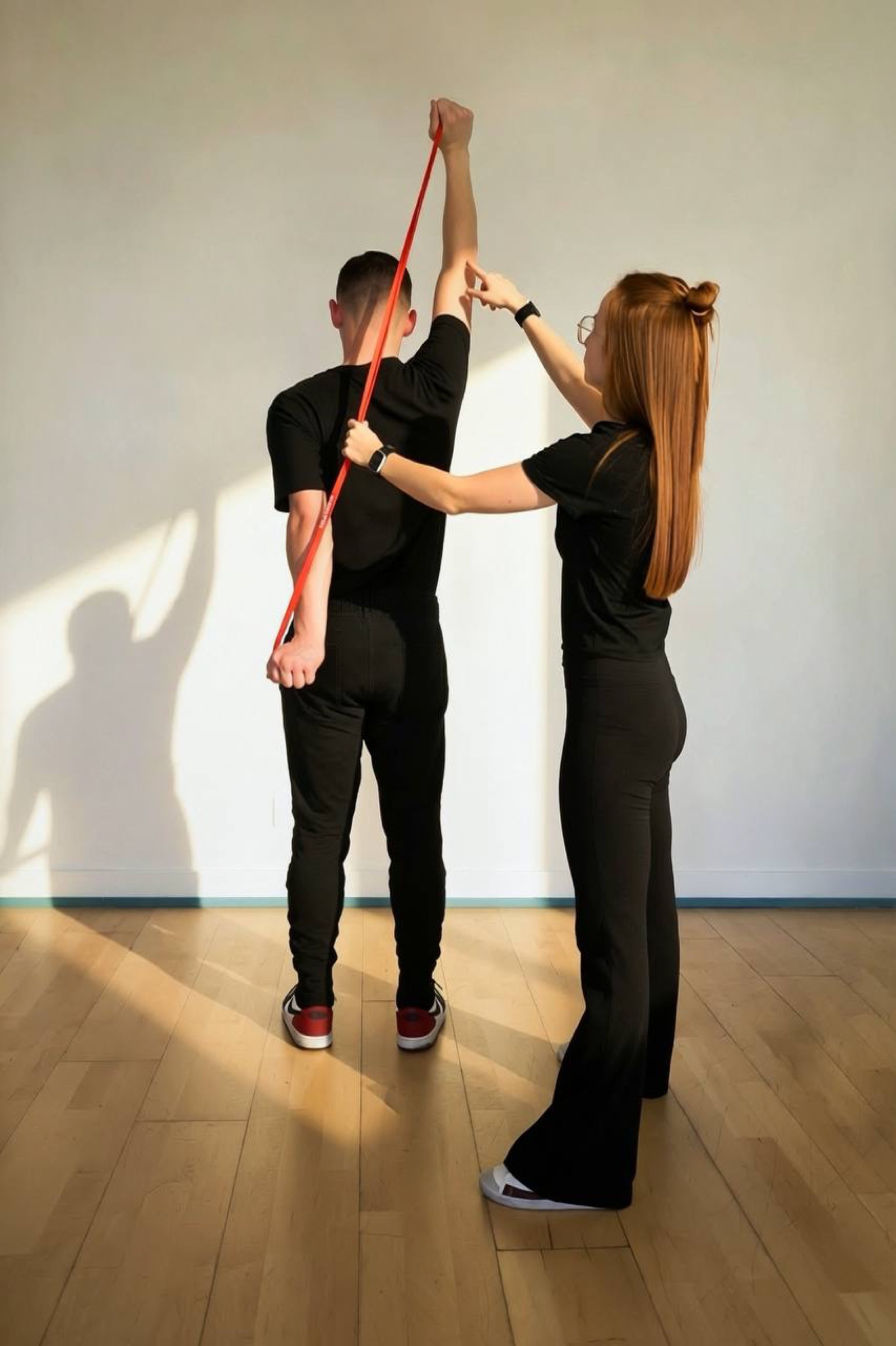 Coach Ilona guiding an athlete's raised arm with a resistance band during a private session